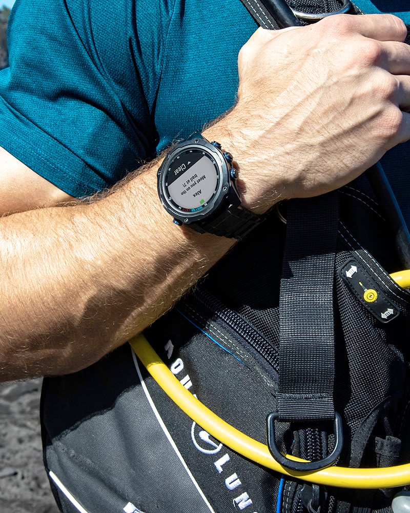 Garmin Descent Mk2i worn on the wrist over a wetsuit beside a BCD