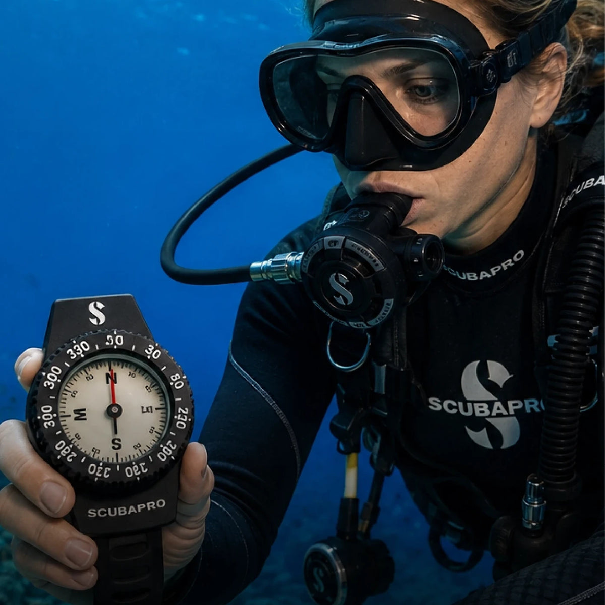 A diver holding out a compass underwater