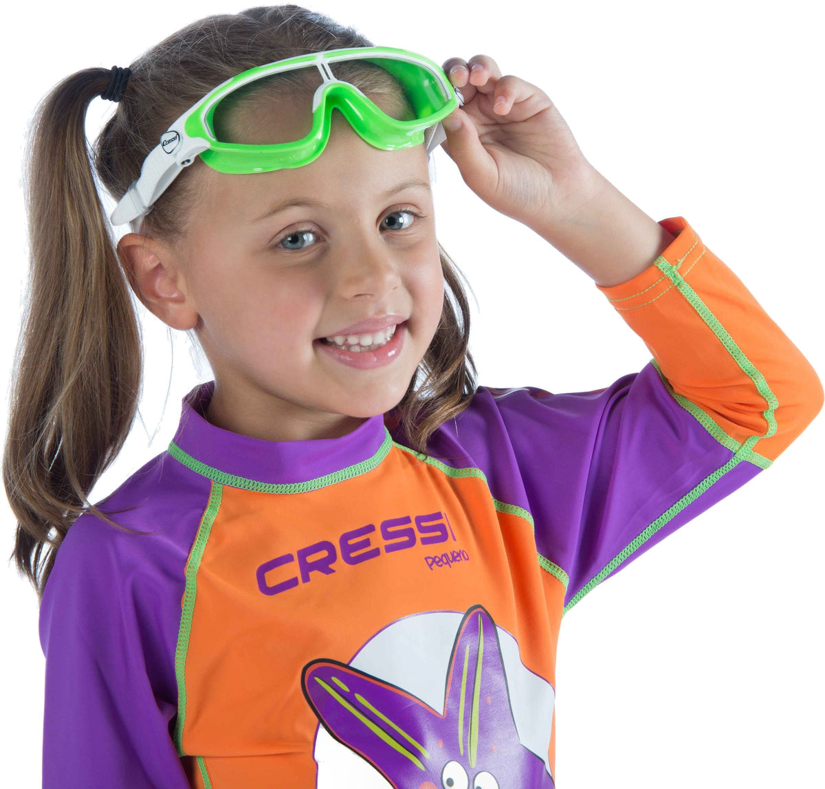 Girl in a Cressi rash vest lifting the lime Baloo goggles onto her forehead