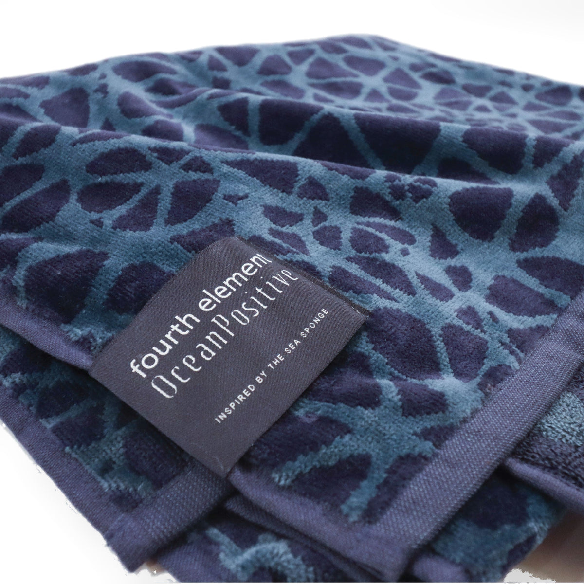 Close-up of the OceanPositive woven label stitched to the edge of the Fourth Element beach towel