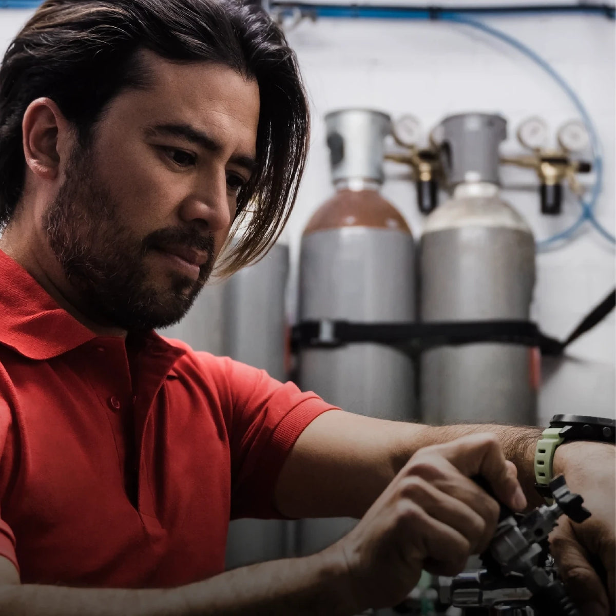 A technician working on a cylinder manifold at a fill station