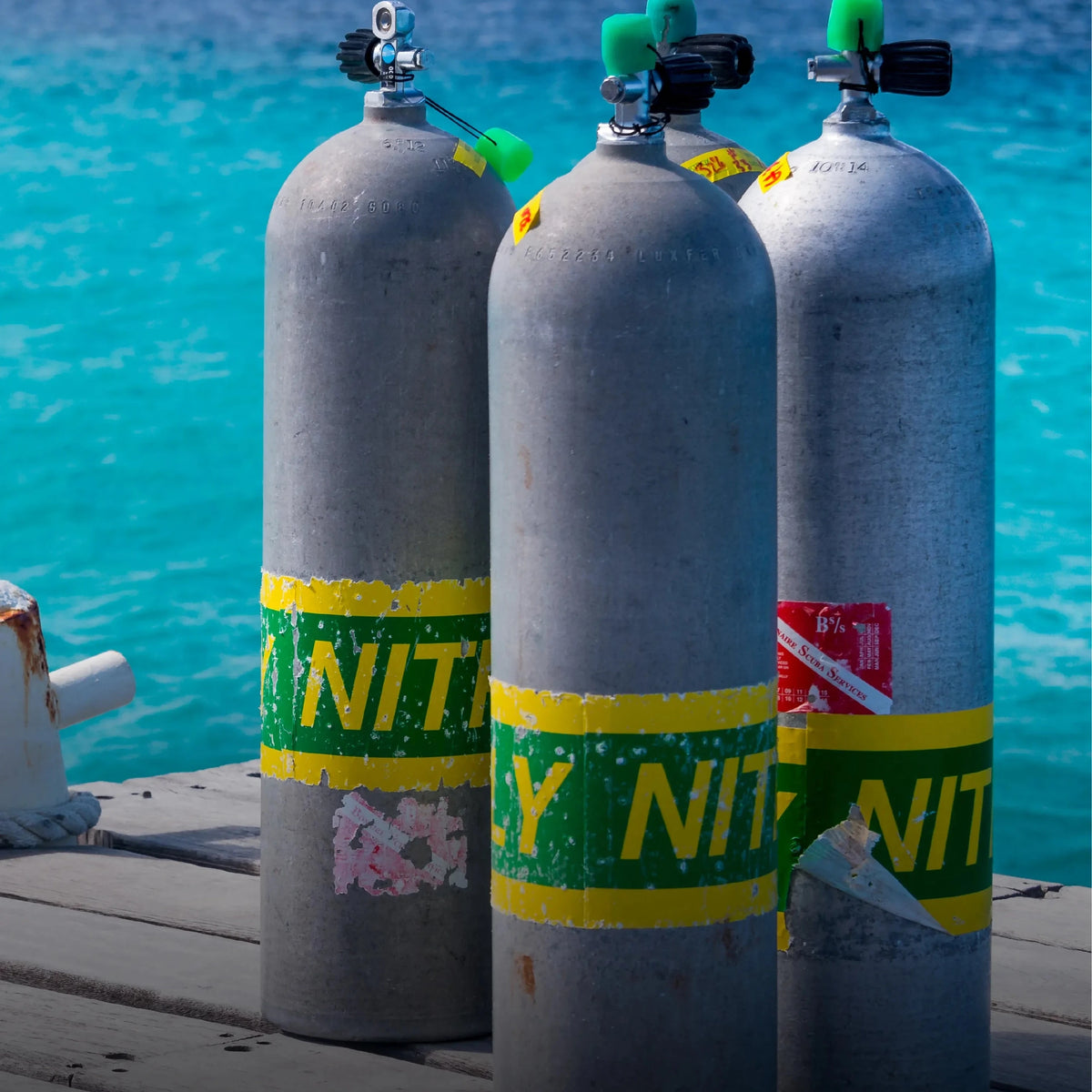 Three cylinders banded with nitrox tape on a jetty