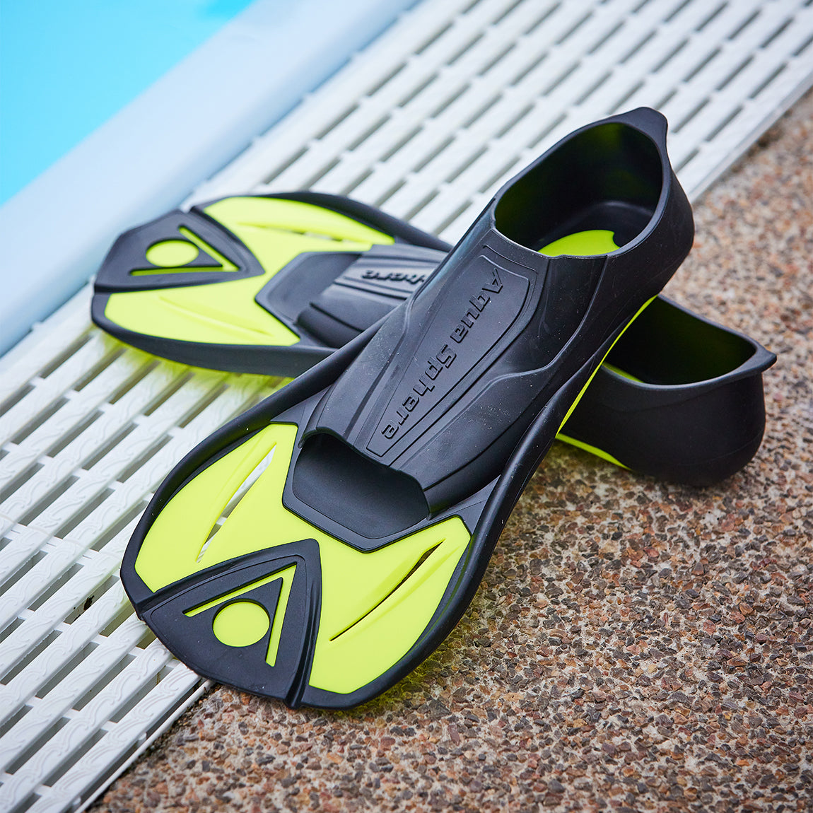 Pair of black and yellow Microfin short blade fins on a pool deck