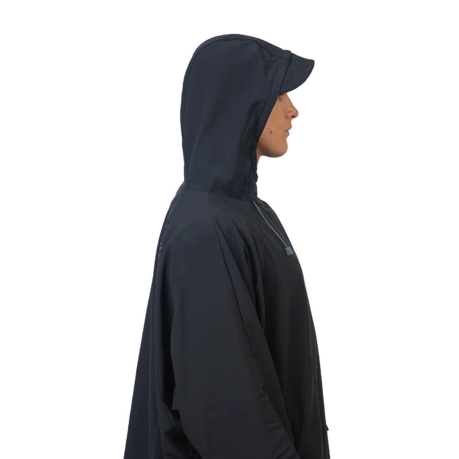 Fourth Element Storm poncho in black worn front on with the hood down