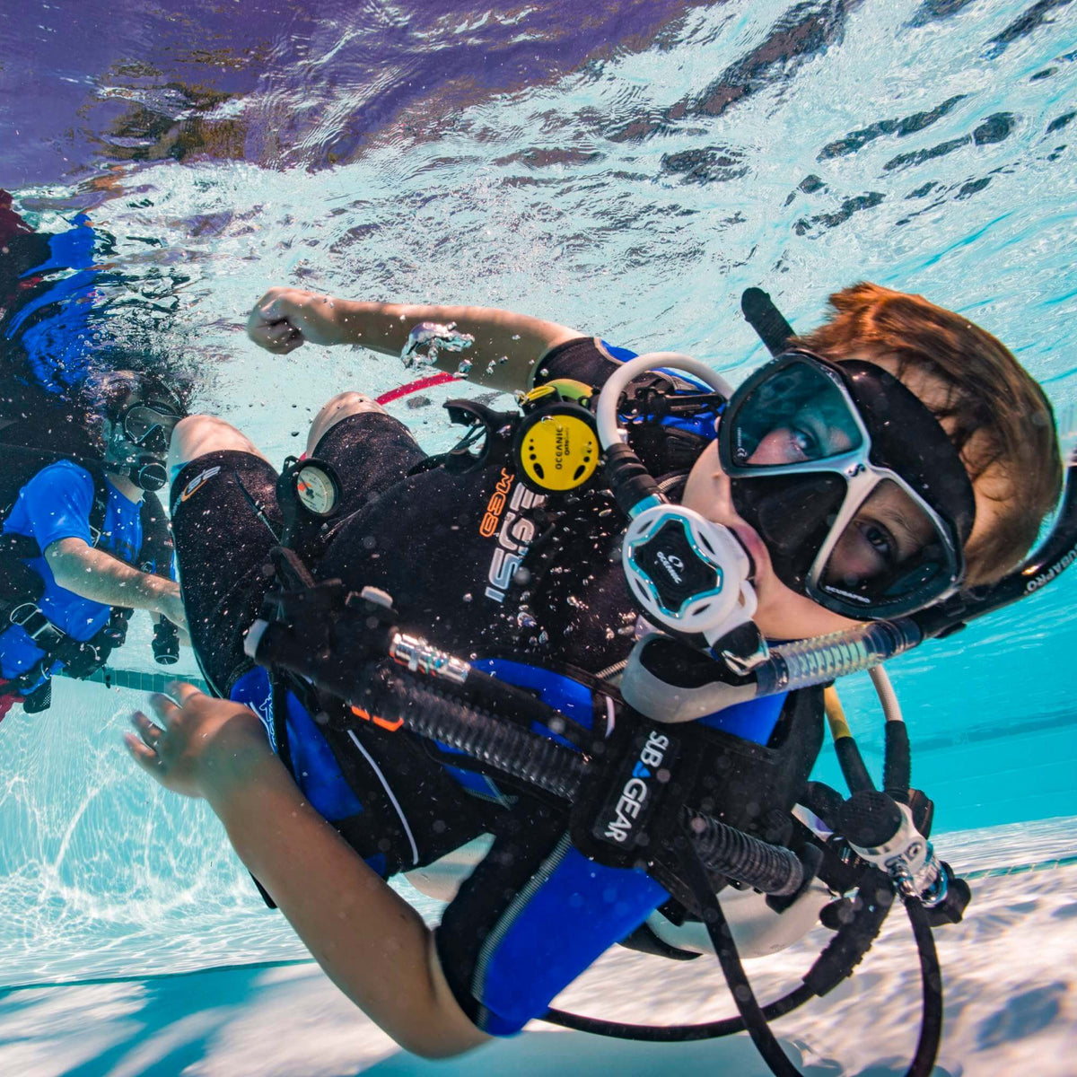 Child in scuba kit swimming in a pool on a PADI Seal Team session