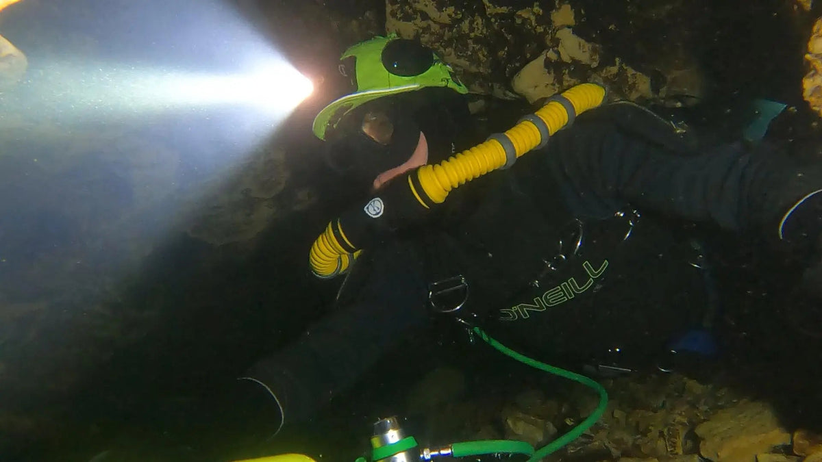 Diver in a cave passage wearing an OrcaTorch Mazu TD01 headlamp