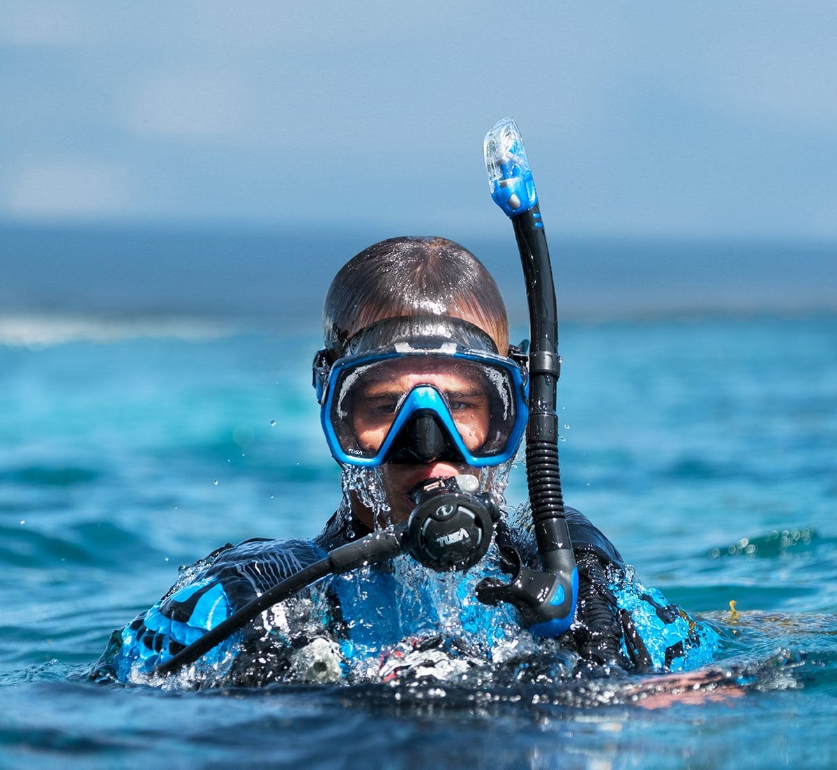 Snorkeller at the surface in a blue Tusa Freedom HD mask