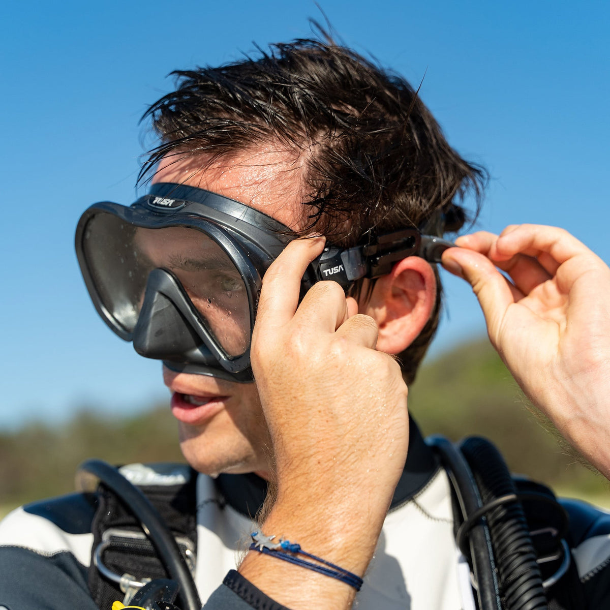Diver fitting a black Tusa Zensee mask on a boat