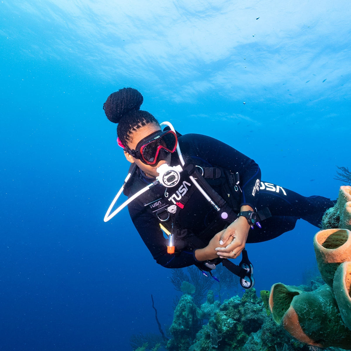 Diver swimming over a reef wearing a Tusa Ino mask