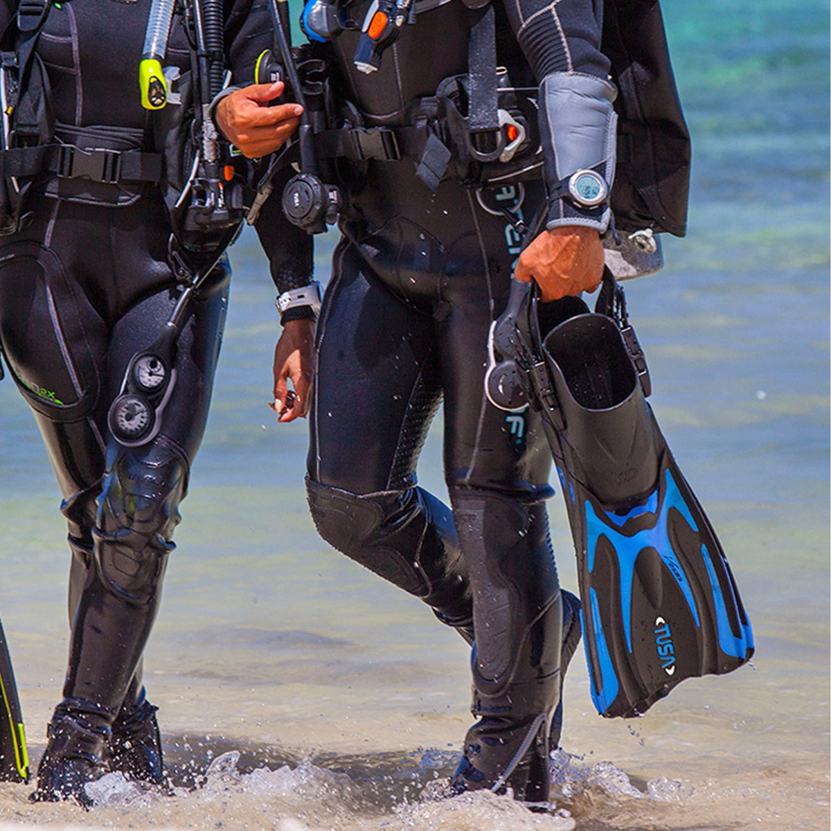 Divers walking out of the sea carrying Tusa Hyflex Vesna fins