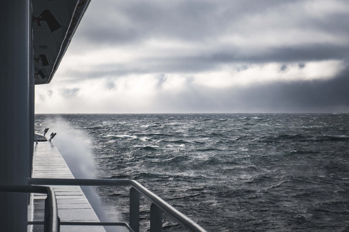 Grey chop seen over the rail of a vessel under an overcast sky.