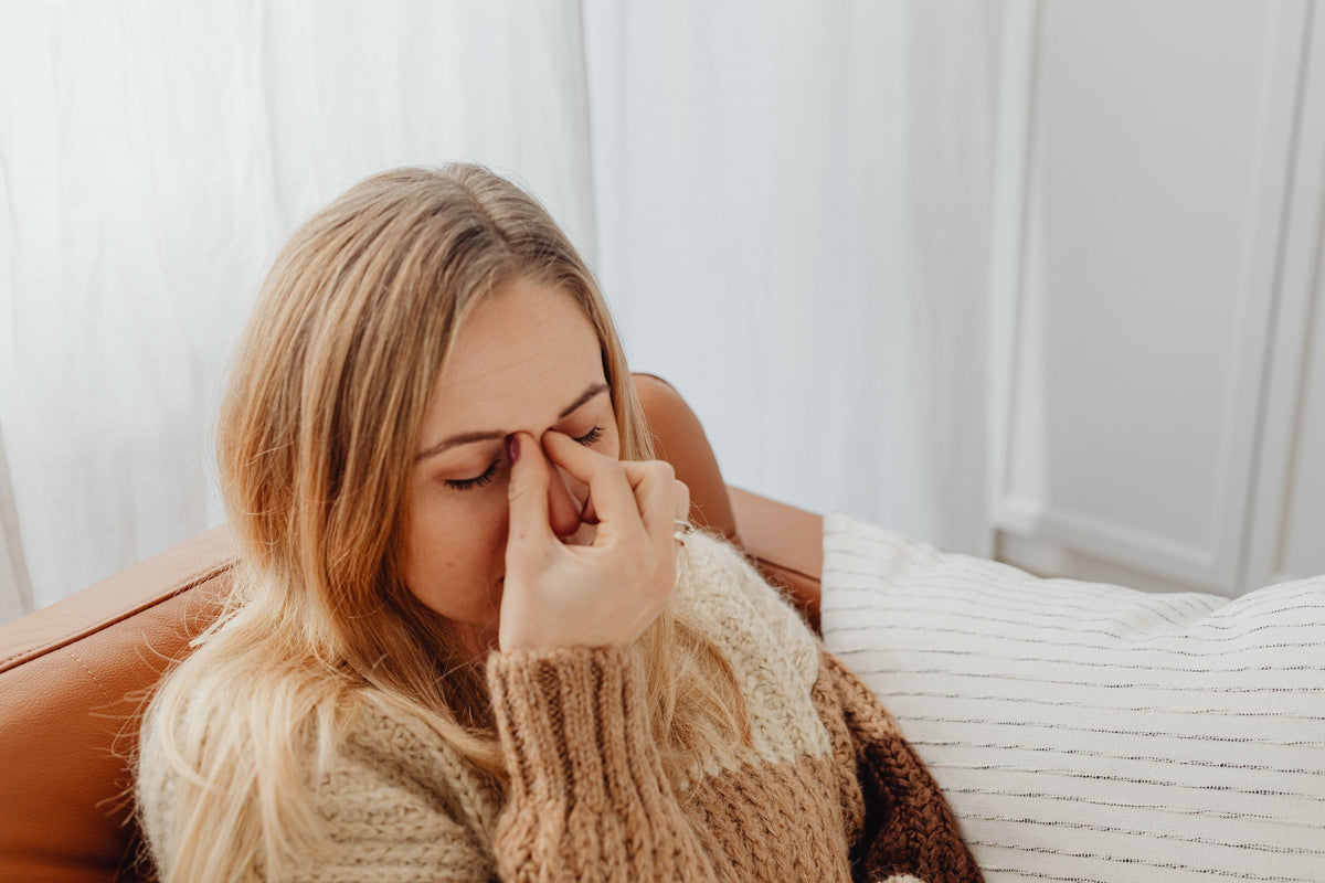A person pinching the bridge of the nose with sinus pain