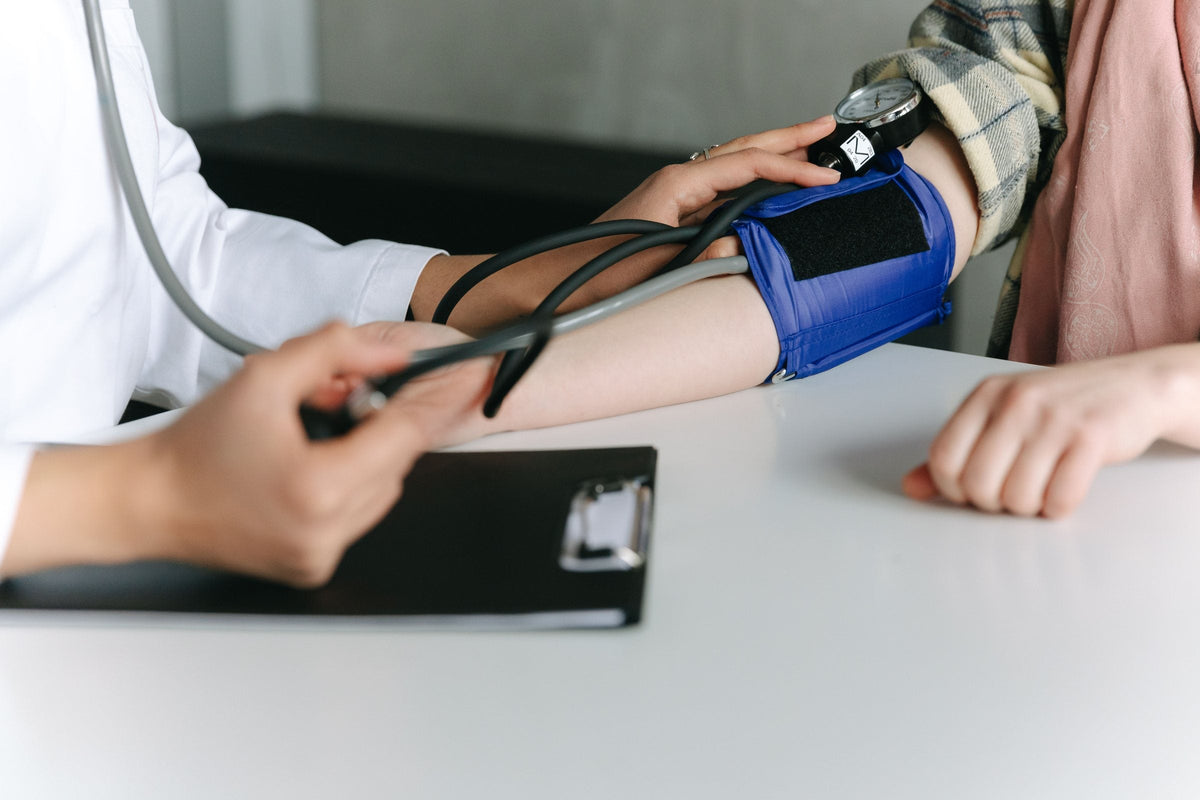 A healthcare worker taking a blood pressure reading with a cuff and stethoscope