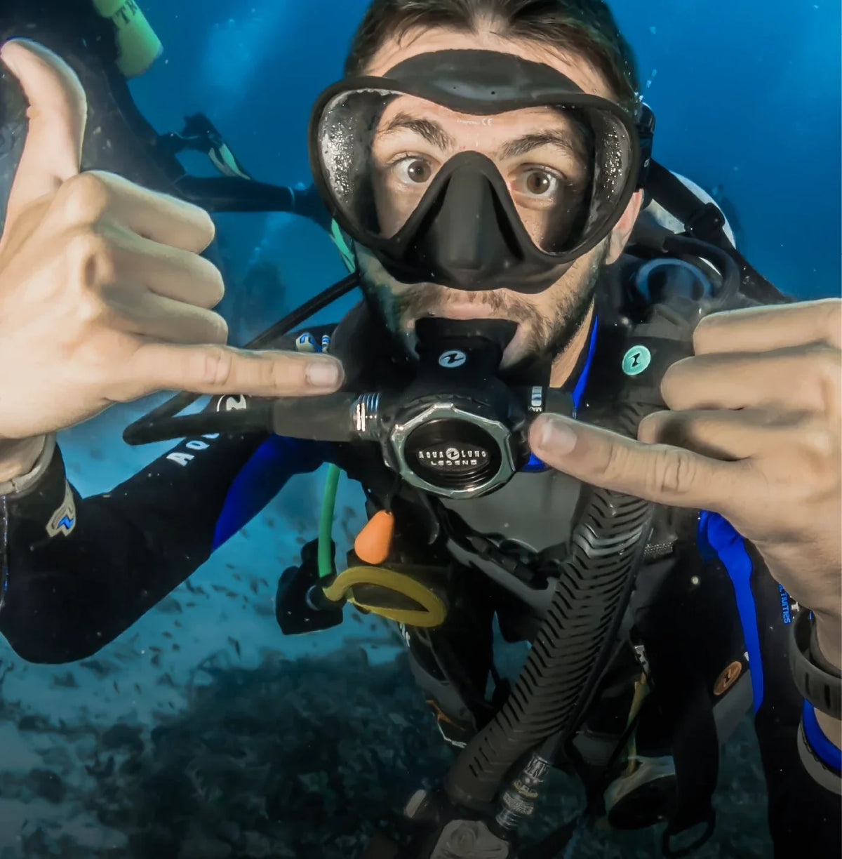 A diver checking a wrist computer in mid-water