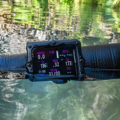 Diver wearing a black Shearwater Perdix 3 dive computer on the wrist underwater