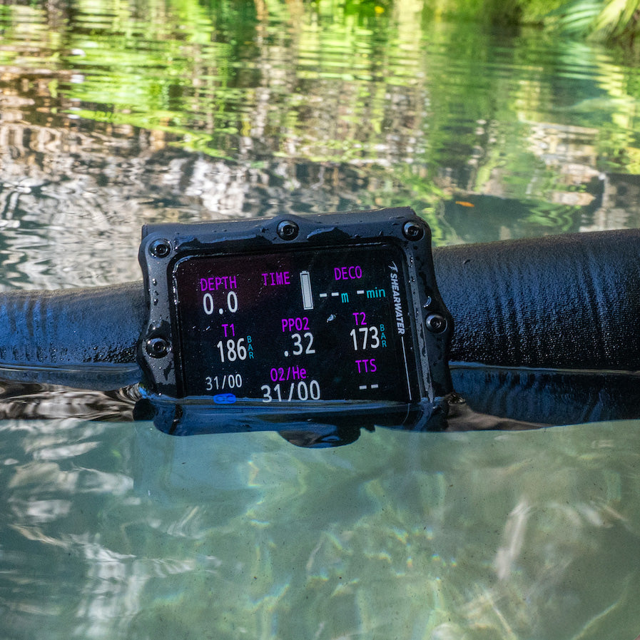 Diver wearing a black Shearwater Perdix 3 dive computer on the wrist underwater