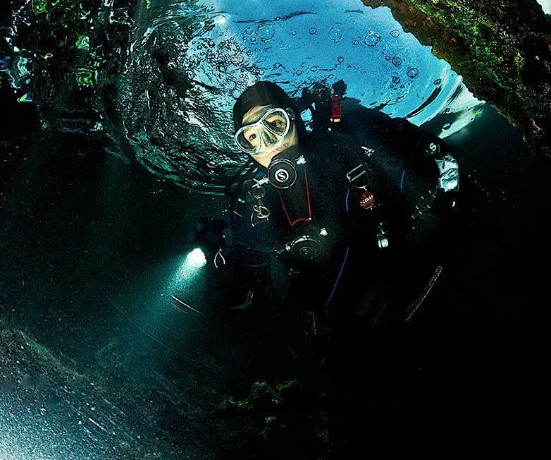 Divers in a cave passage lit by an OrcaTorch D860