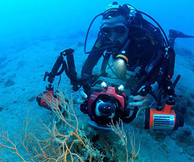 Diver with a camera rig lit by OrcaTorch D910V video lights