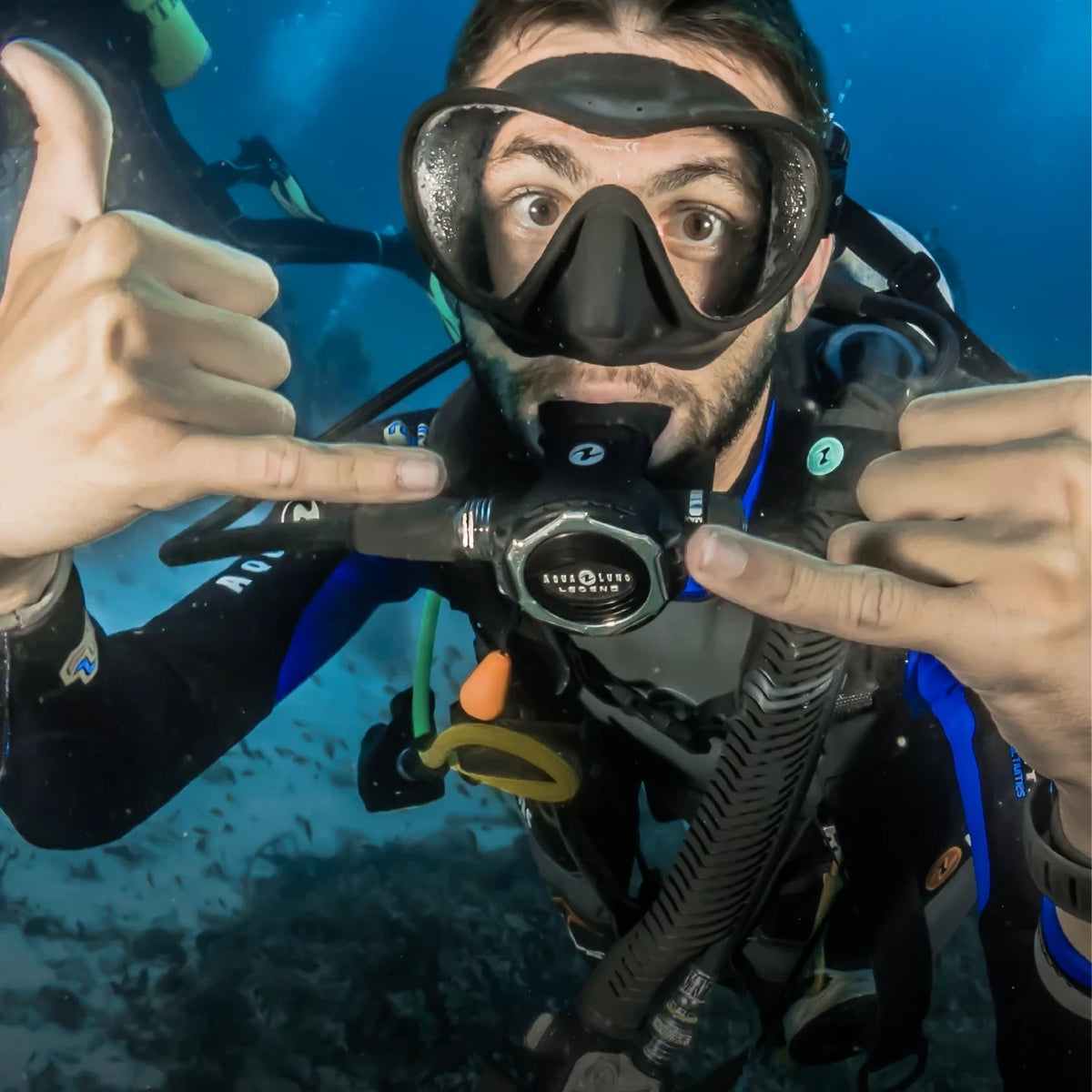 A diver checking a wrist computer in mid-water