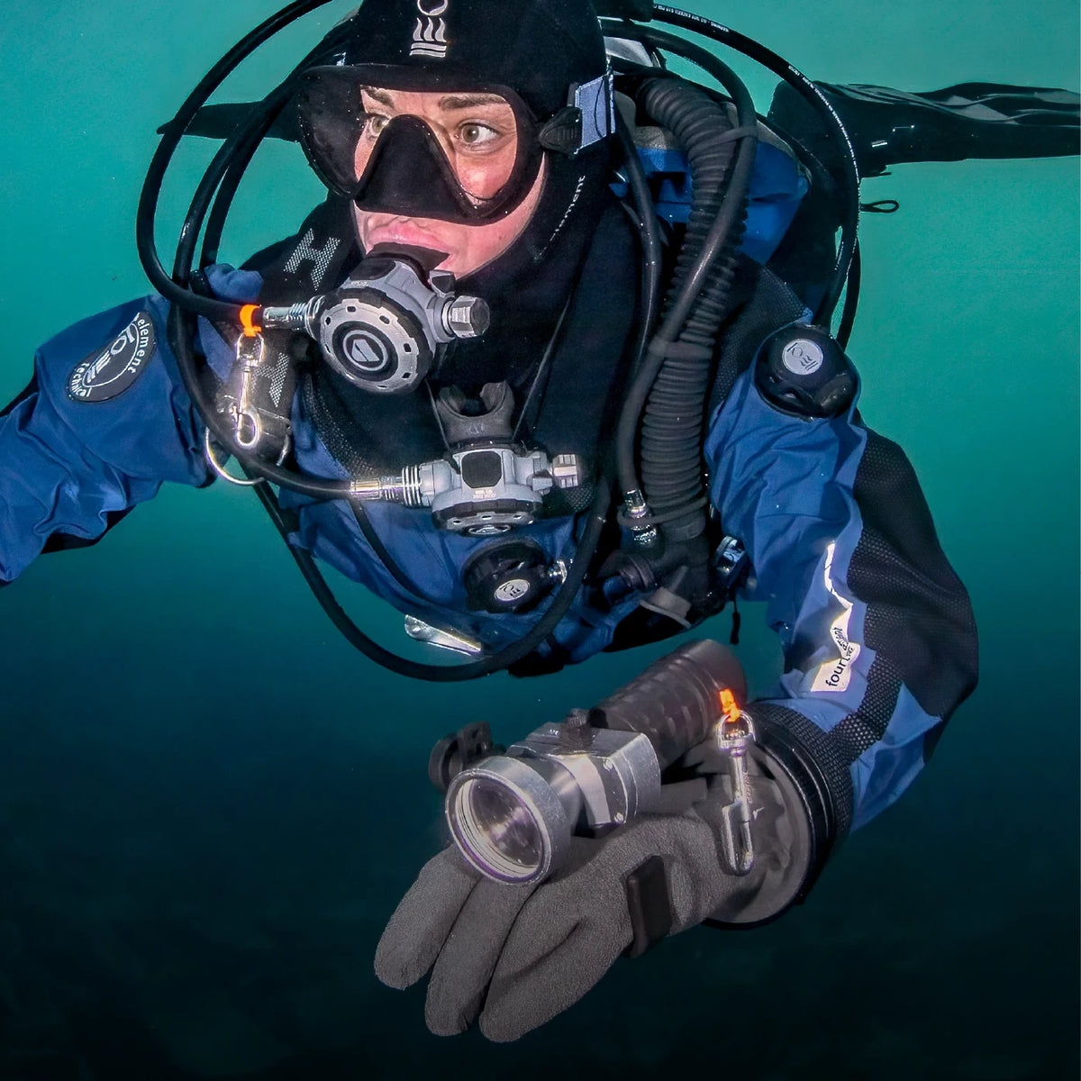 A diver in a blue drysuit and dry gloves in mid-water
