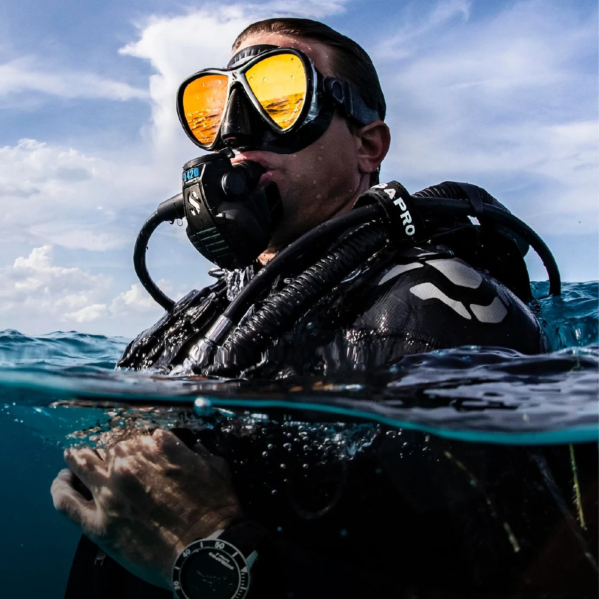 A diver at the surface in full kit against a blue sky