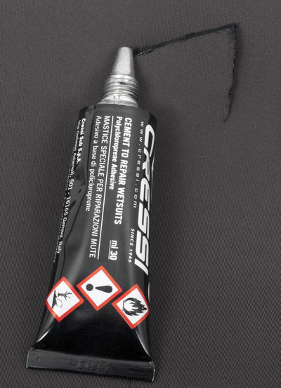 Tube of Cressi neoprene glue on a grey surface with a thin bead squeezed from the nozzle