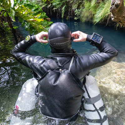 Shearwater Perdix 3 dive computer held at a cave entrance before a technical dive