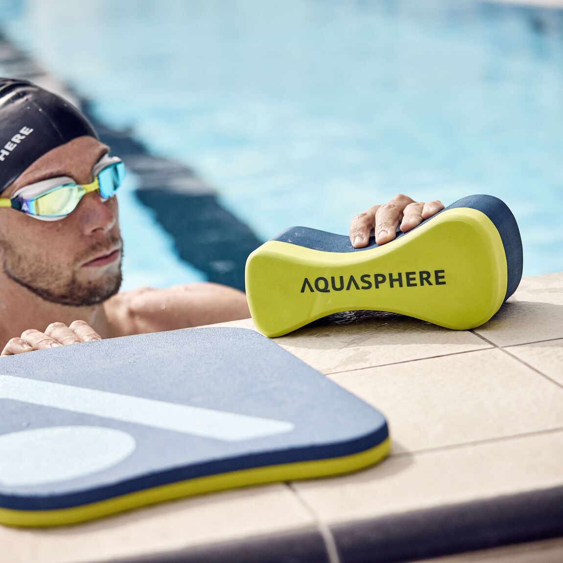 Swimmer at the pool wall with the yellow and navy Aquasphere pull buoy