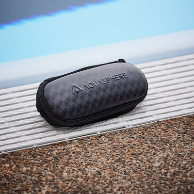 Closed Aquasphere goggle case sitting on a pool deck grating