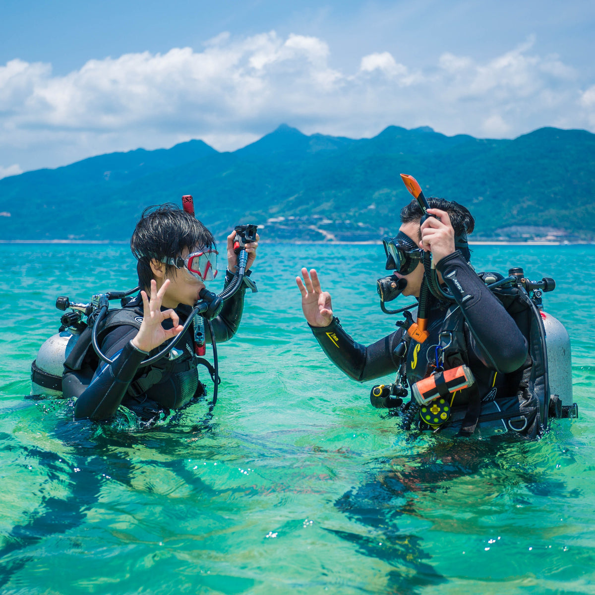 Instructor and student exchanging hand signals in clear shallow water
