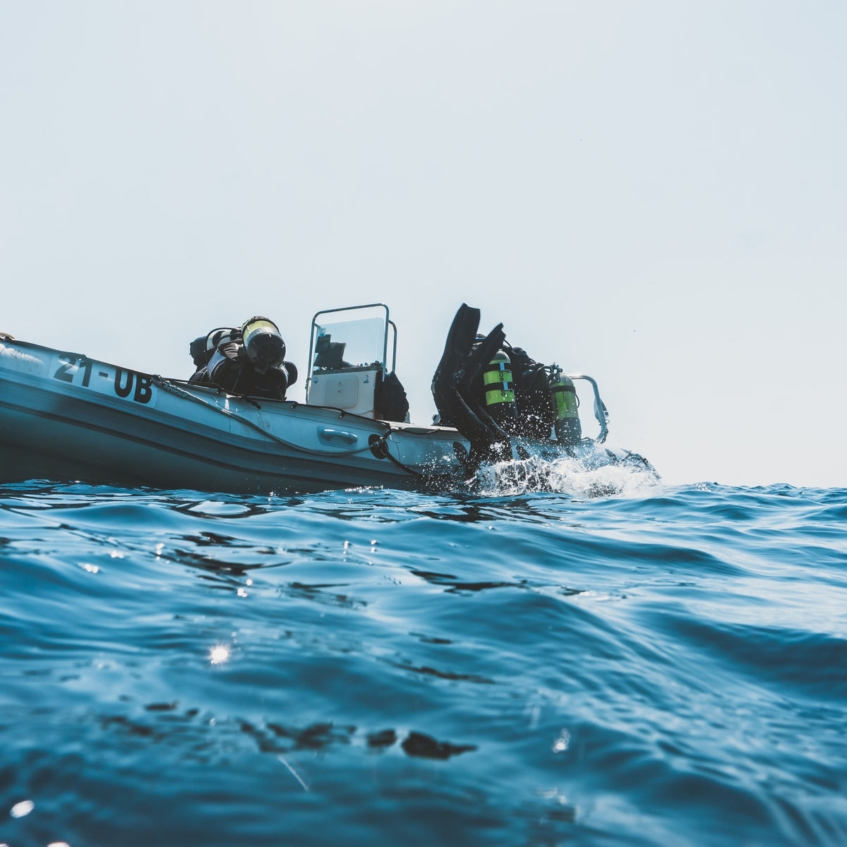 Divers back-rolling off an inflatable dive boat
