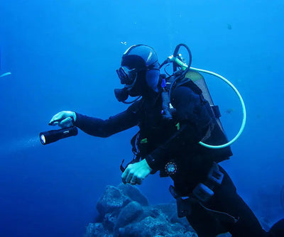 Diver underwater holding an OrcaTorch D860 dive light