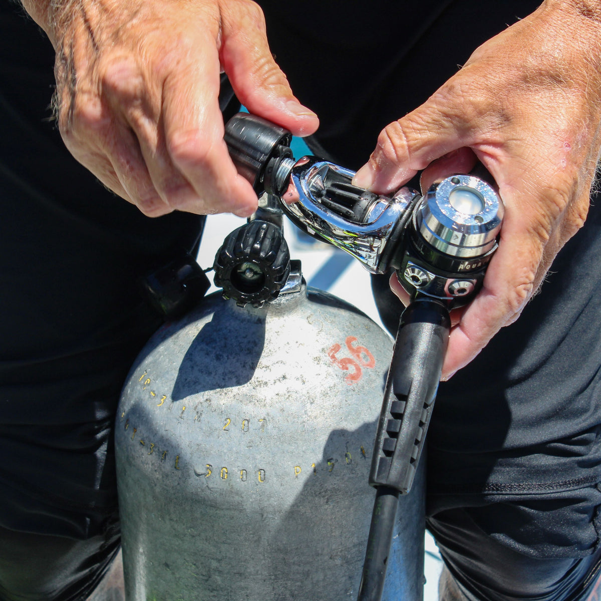 Hands fitting a regulator first stage to a cylinder valve