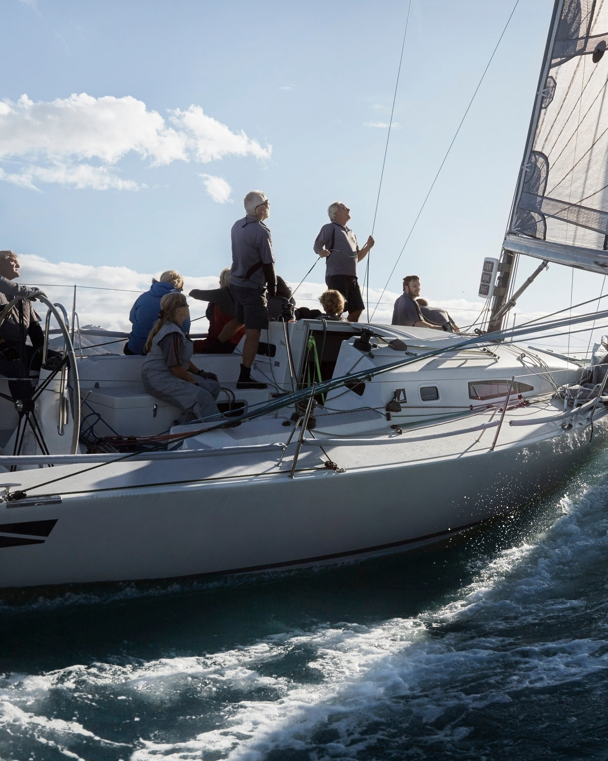 Crew on a yacht heeling under sail through spray