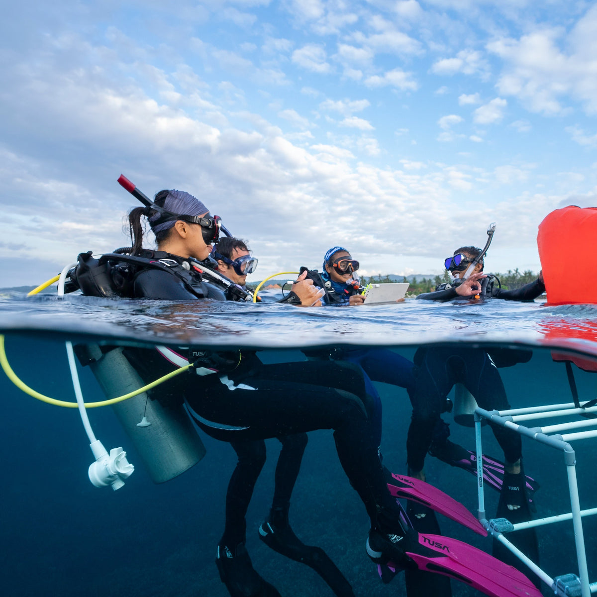Class of new divers at the surface with their instructor and slate