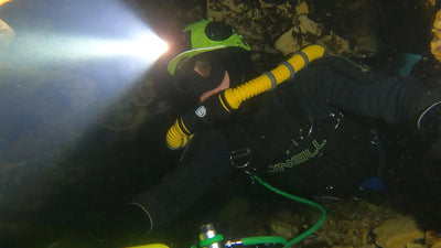 Diver in a cave passage wearing an OrcaTorch Mazu TD01 headlamp
