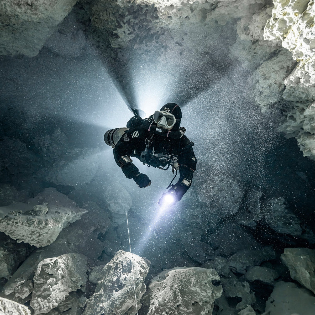 Technical cave diver with a torch following a guideline deep in a cave