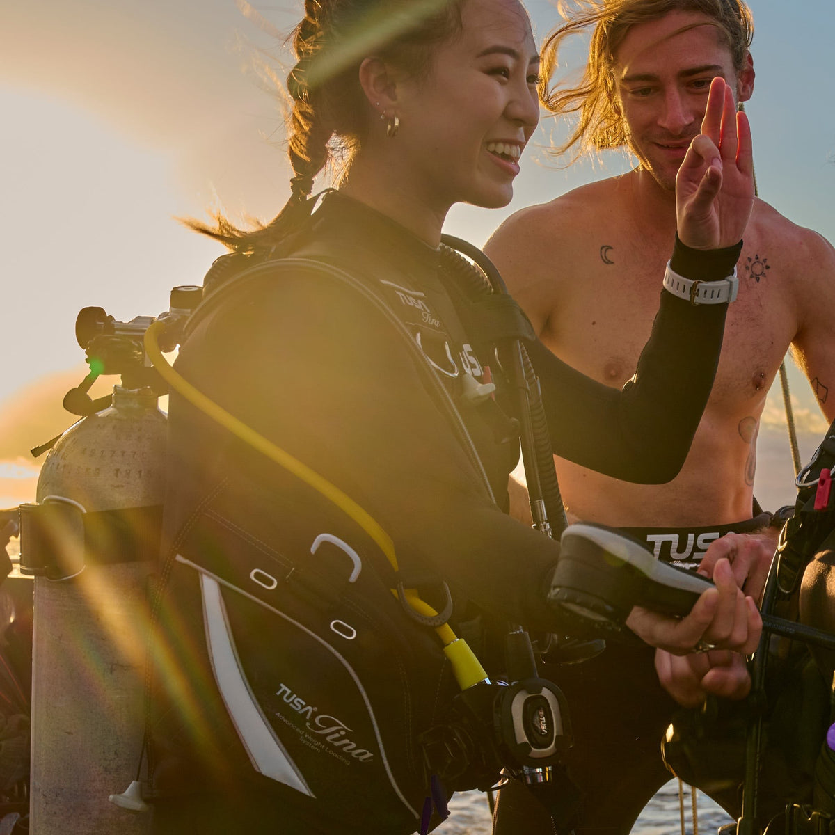 Two divers on a boat, one wearing a Tusa Tina BCD