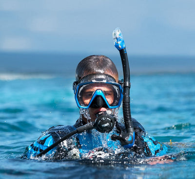 Snorkeller at the surface in a blue Tusa Freedom HD mask