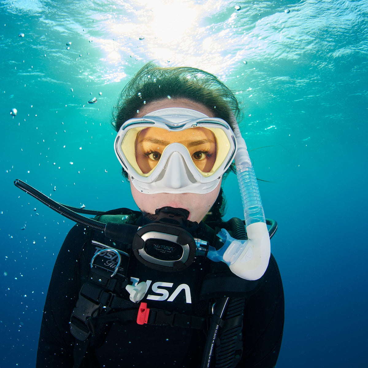 Diver underwater wearing a white Tusa Paragon S mask