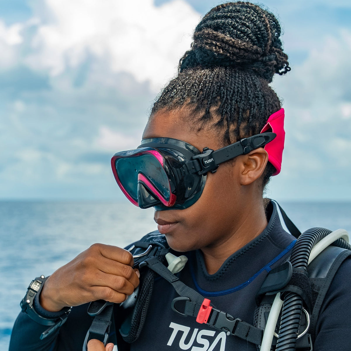 Diver on a boat adjusting a black and pink Tusa Ino mask