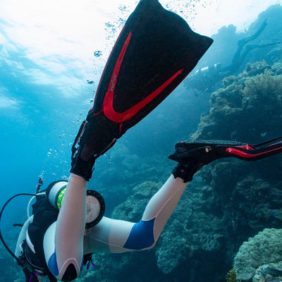 Scuba diver finning down a reef slope wearing Tusa Hyflex Switch fins