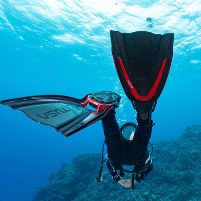 Diver kicking with red Tusa Hyflex Switch fins over a reef